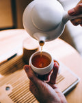 tea pot pouring a cup of Coastie Breafast Tea into a small white cup